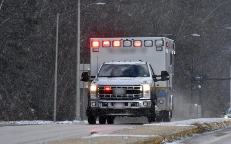 Ambulance with lights on driving through falling snow