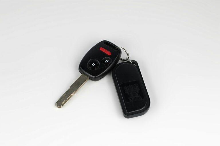 Car key and remote fob on a plain light surface.