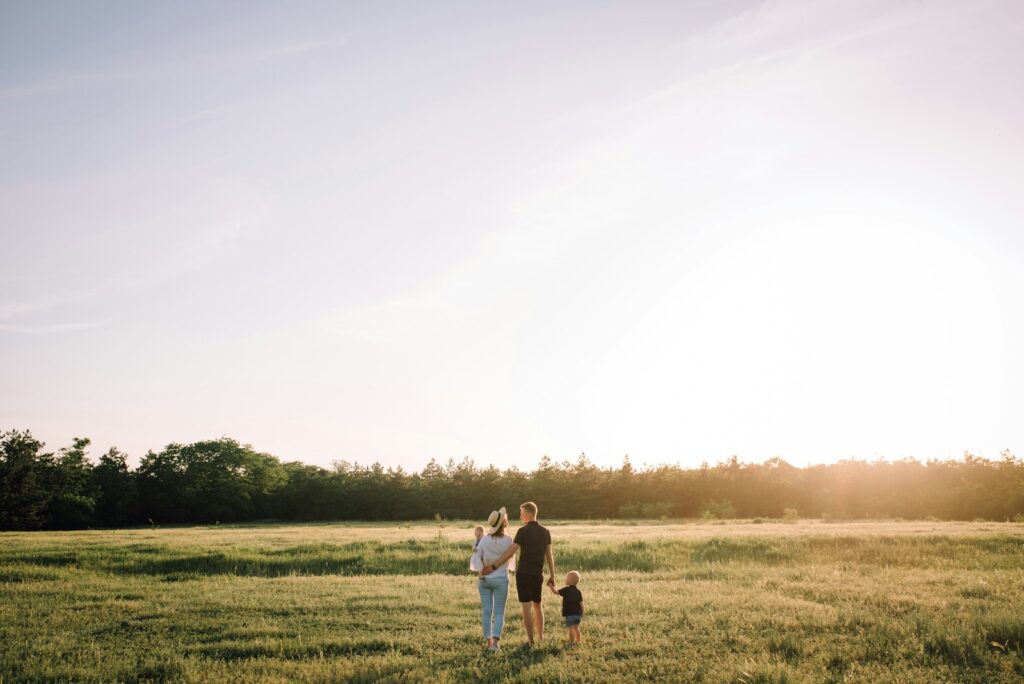 Two adults and two children in a grassy field at sunset.