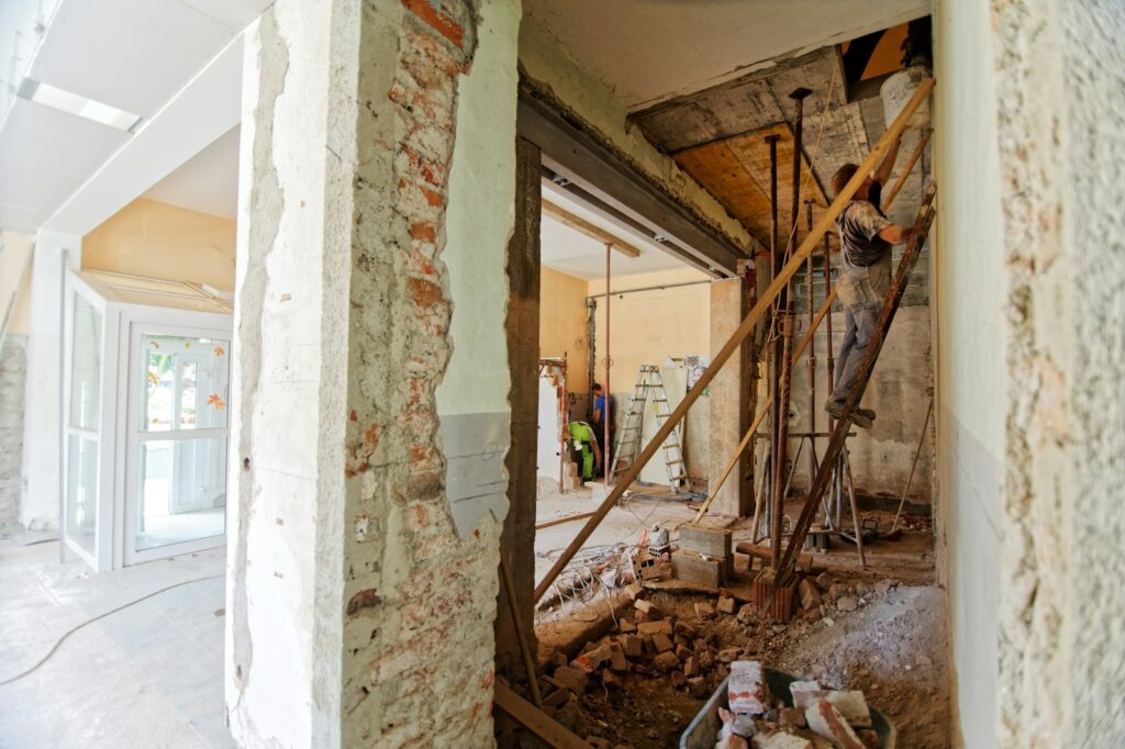 Worker on a ladder inside a room undergoing renovation.