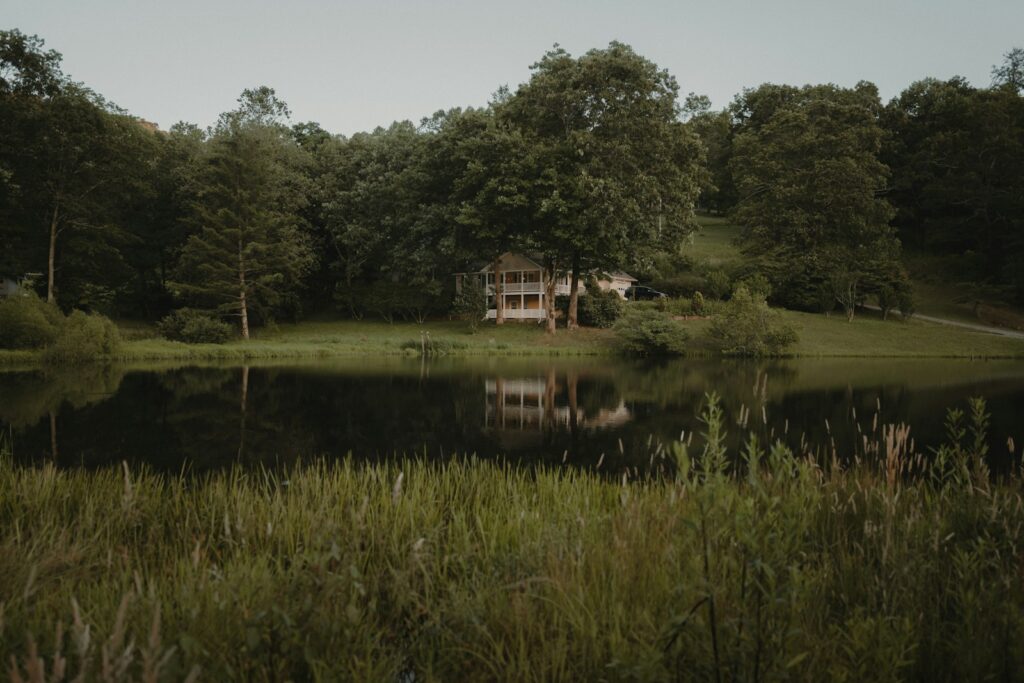Wooded lakeside property reflected in calm water.