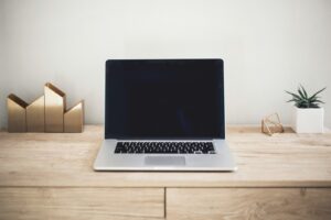 Open laptop with a blank dark screen on a tidy wooden desk.