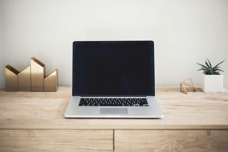 Open laptop with a blank dark screen on a tidy wooden desk.