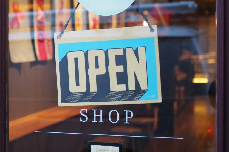 An OPEN SHOP sign hanging in a storefront window.