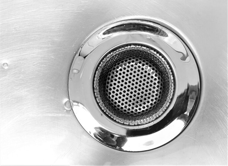 Close-up of a metal sink drain with water droplets.